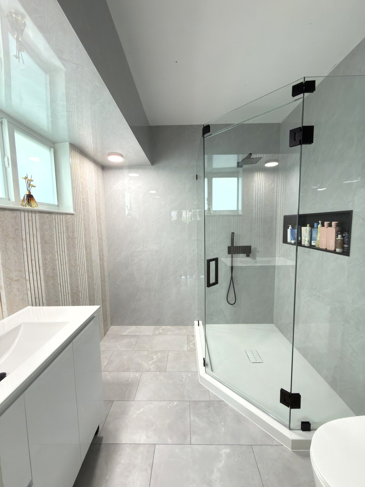 The same bathroom after — frameless corner shower with seamless walls