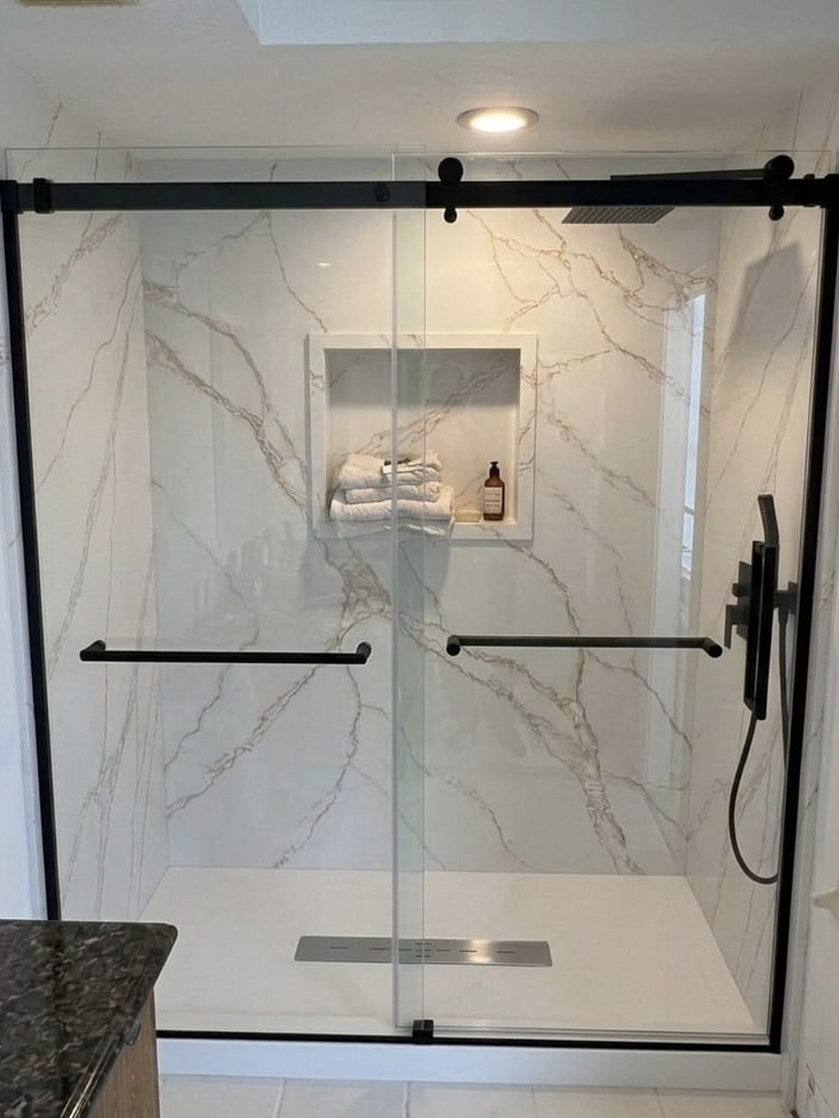 Walk-in shower with solid surface walls and frameless sliding glass